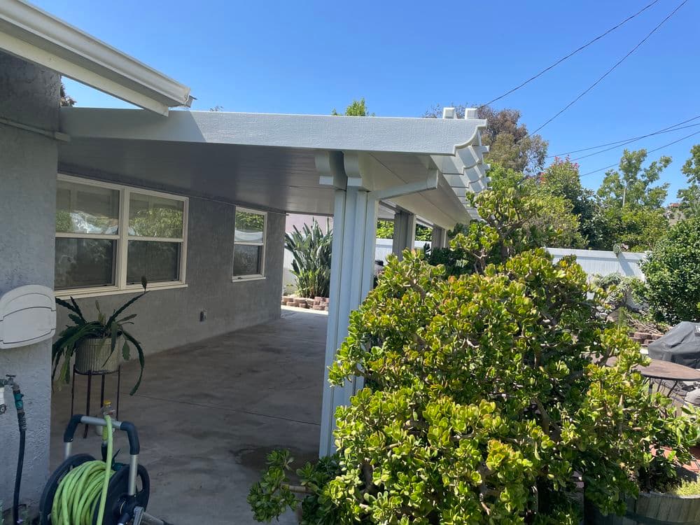 Covered patio area with plants and clear blue sky, showcasing outdoor living space.