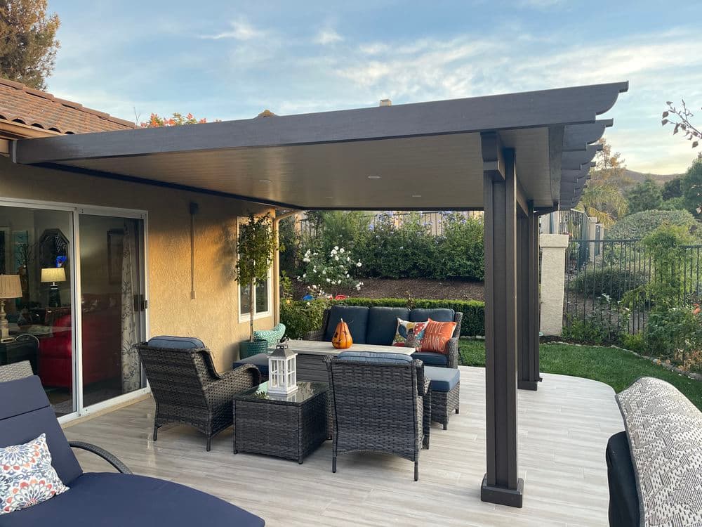 Cozy outdoor living space with a pergola, seating, and lush garden backdrop.