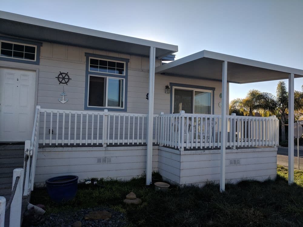 Cozy home exterior with a white porch, palm trees, and nautical decor accents.