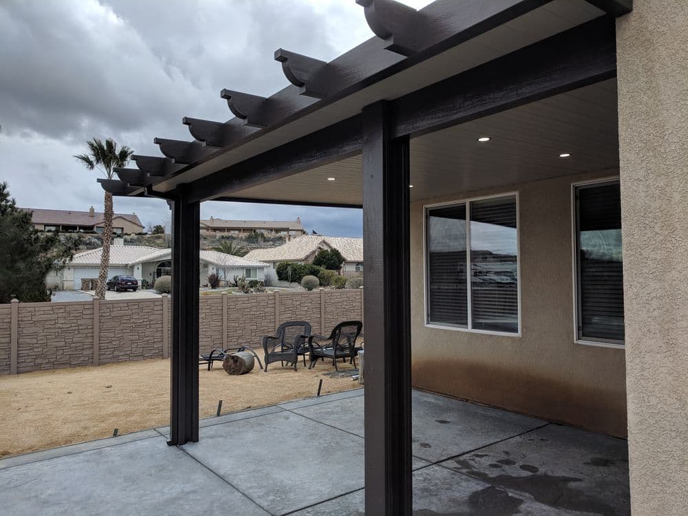 Covered patio with modern design, desert landscape, and cloudy sky in the background.