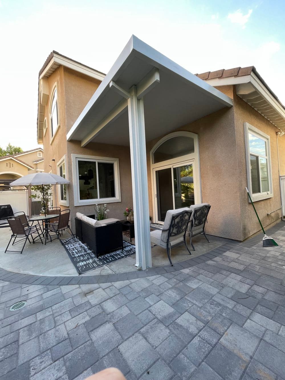 Modern patio with seating area, umbrella, and outdoor decor in a residential backyard.