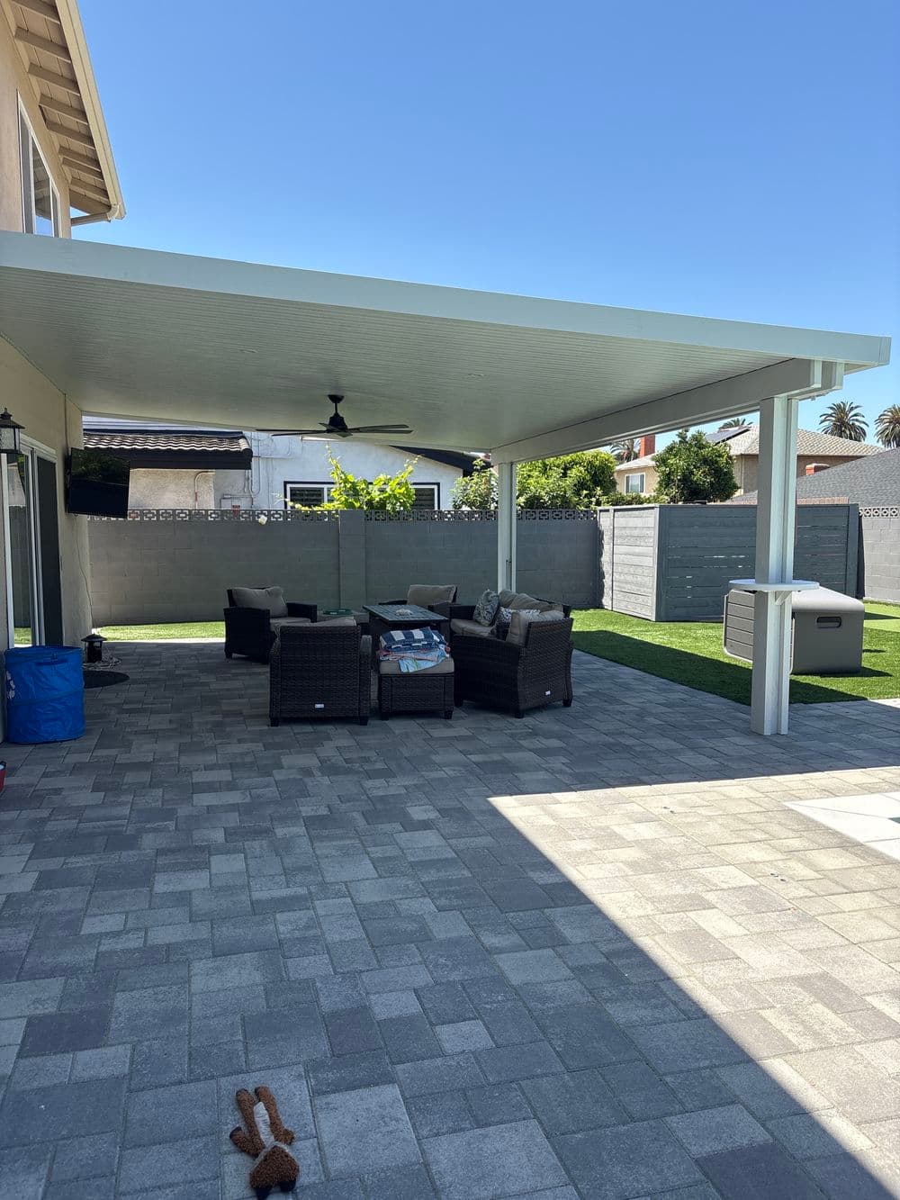 Backyard covered patio with seating area, modern design, and paved flooring.