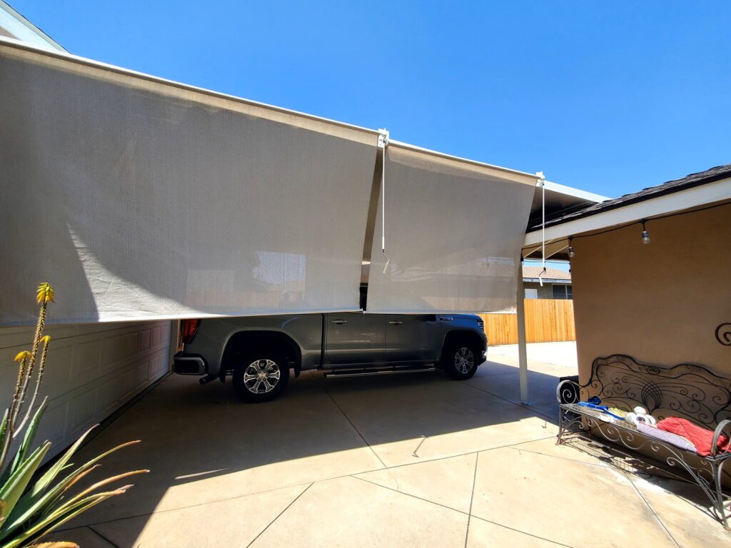Exterior roll-down shade screens installed along a covered residential driveway